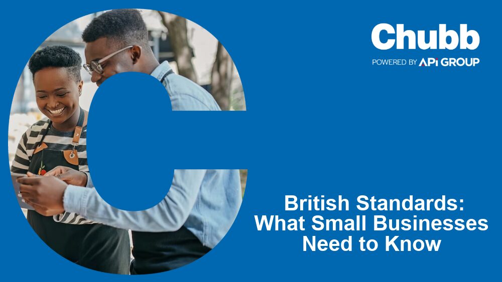 Two small business owners stand together smiling at a smartphone, framed by a large blue “C”, alongside Chubb branding and the headline “British Standards: What Small Businesses Need to Know”, promoting SME fire‑safety guidance and compliance support.